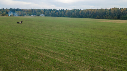 Aerial view of group of fox hunters on the horses in the autumn field. Equestrian riding sport in a...