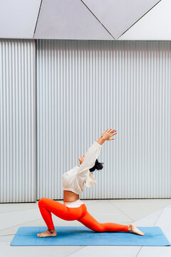 Female athlete doing backbend pose on exercise mat