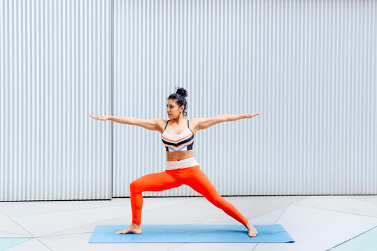 Female athlete in warrior position in front of wall