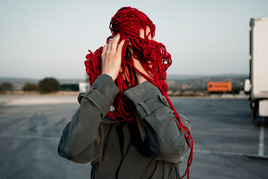 Mid adult woman covering face with thread standing on road