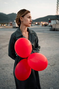 Beautiful woman holding red balloon while looking away
