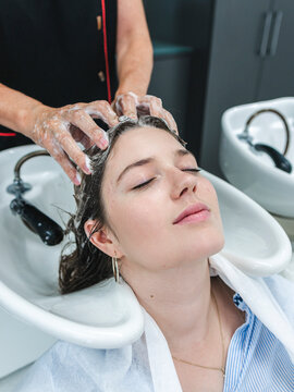 Master washing dark hair of female customer