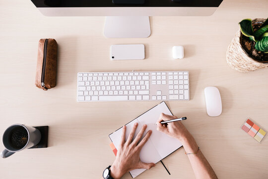 Crop employee making notes on working desk