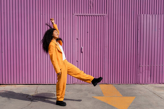 Happy young woman dancing on footpath by cabin