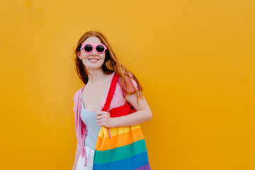 Smiling woman with multi colored bag standing in front of wall