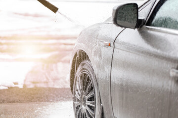 Purifying automobile with touchless technology in exterior carwash. Cleaning car with high pressure...