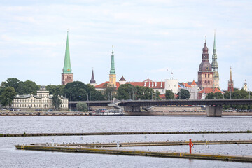 Obraz premium Cityscape view of Old Riga house and church towers in background and yach pier in foreground.