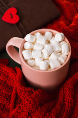 Cup with cocoa and marshmallows. Coffee with marshmallows. Red scarf. The concept of warmth and comfort