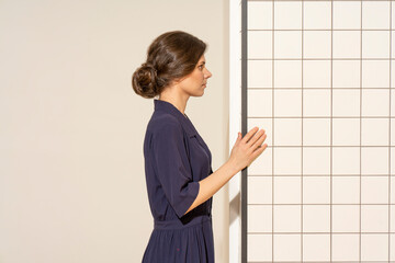 Young woman looking at white tile wall