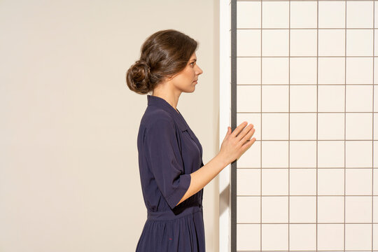 Young woman looking at white tile wall