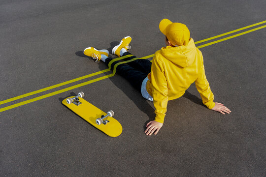 Yellow adhesive tapes over boy's legs by skateboard on road