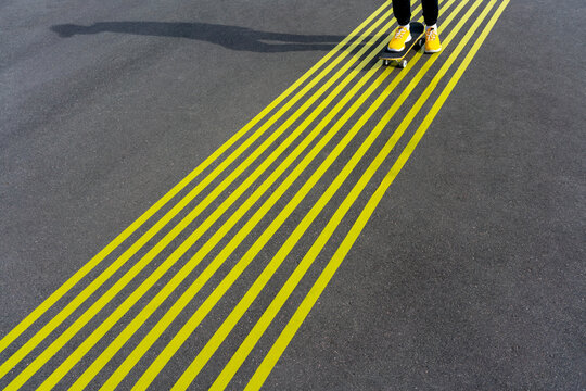 Boy skateboarding over yellow markings on road
