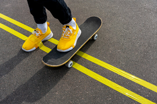 Yellow adhesive tape on boy's shoe while skateboarding on road