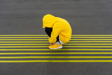 Depressed boy crouching on striped yellow road markings