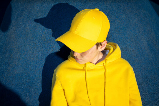 Boy wearing yellow cap and sweatshirt at skateboard park