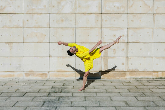 Young man practicing dance in front of wall