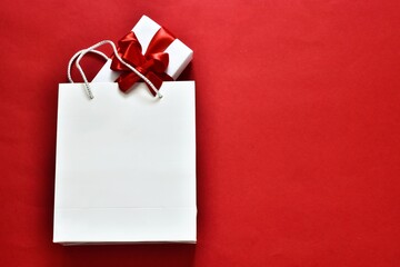 Black Friday sale. Black Friday sale shopping. White paper shopping bag and gift box on a red background. Flat lay, copy space. Advertising