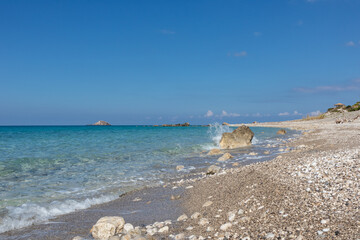 Wave splashes on white pebbles beach close-up with azure clear water on coast of Lefkada island in Greece. Summer nature vacation travel to Ionian Sea