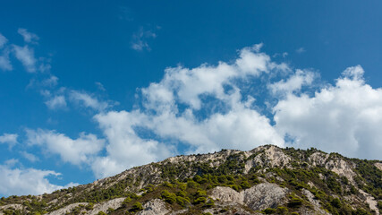 Green cliffs on sunny bright clear blue day in Greece. Trees and bushes on rocky mountains with clear blue sky, Lefkada island, Ionian sea coast