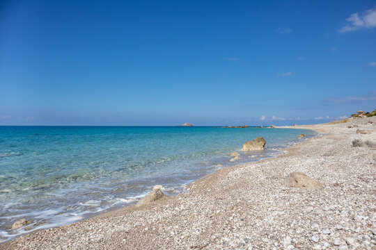 White pebbles and rocks on beach close-up with azure clear water on coast of Lefkada island in Greece. Summer nature vacation travel to Ionian Sea