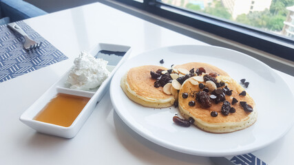 Stack of pancakes topping with chocolate chip on white plate
