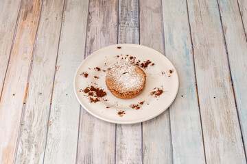 Cookie filled with chocolate with icing sugar and cocoa powder on wooden table