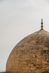 Ancient stone dome gilded by sunlight and crowned by Muslim decoration