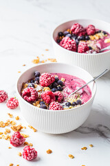 Berry smoothie bowl with granola, coconut and hemp seeds, marble background. Vegan food concept.