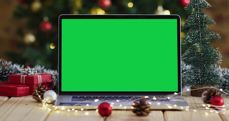 Laptop with green screen on screen, with christmas decorations and tree