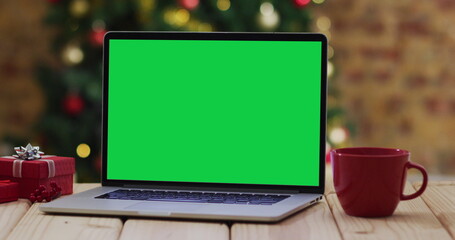 Laptop with green screen on screen, with christmas decorations and tree