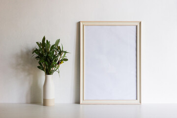 A white frame with green leaves on table with nature lgiht.