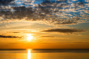 Sunset over the sea. Reflection of sunlight in the sea waves. The sky in the sunset rays.