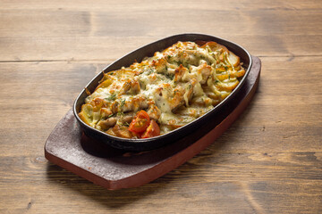 Baked meat with fresh vegetables and sauce in low pot