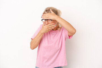 Young Russian woman isolated on white background blink at the camera through fingers, embarrassed covering face.