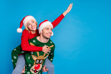 Obraz premium Photo portrait funny couple wearing xmas outfit waving hands looking copyspace piggyback isolated vibrant blue color background