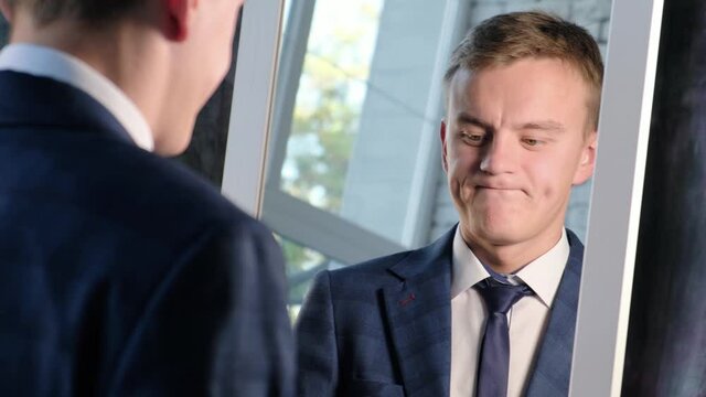 Depressed man in business suit looks at himself in the mirror