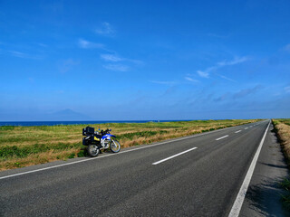青空と地平線へ延々と遠くに続く道とバイク