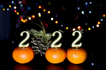 Number 2022 gold color and cone with golden bow on dark background with New Year's bokeh. Concept of Christmas, new year.