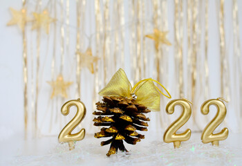 Number 2022 gold color and cone with golden bow, golden background and stars. Concept of Christmas, new year.