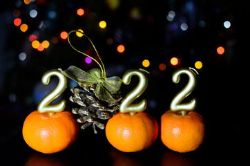Number 2022 gold color and cone with golden bow on dark background with New Year's bokeh. Concept of Christmas, new year.