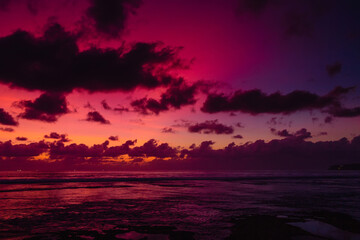 Colorful bright sunset or sunrise with clouds at tropical beach.