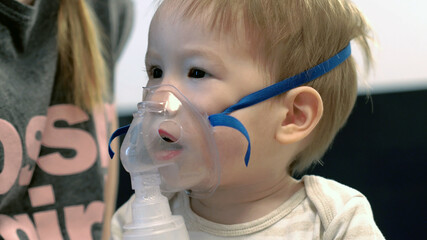 Close up of baby boy himself using steam inhaler nebulizer mask