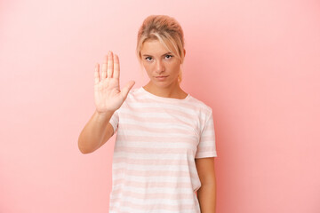 Young Russian woman isolated on pink background standing with outstretched hand showing stop sign, preventing you.