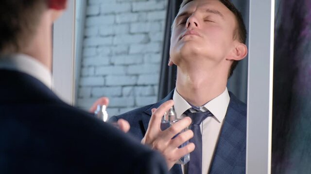 A man applies perfume while standing in front of the mirror before leaving the house
