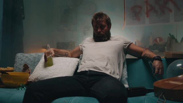 Man drinking alcohol on sofa in smoky room