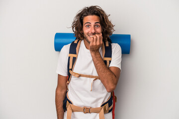 Young hiker caucasian man isolated on gray background biting fingernails, nervous and very anxious.