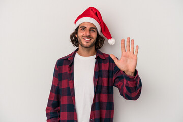 Young caucasian man celebrating Christmas isolated on gray background smiling cheerful showing number five with fingers.