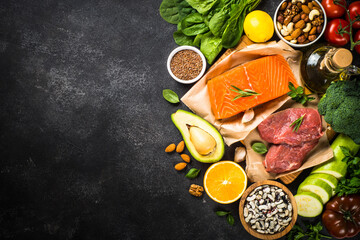 Keto diet food. Healthy food products at black background. Salmon steak, beef, beans, nuts,...