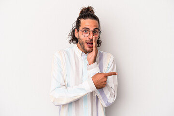 Young caucasian man isolated on gray background saying a gossip, pointing to side reporting something.