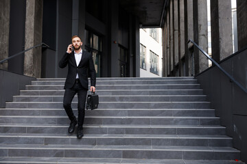 Smiling businessman goes downstairs in a stylish suit on the str